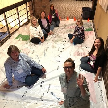 Librarians sitting on the giant map of Montana