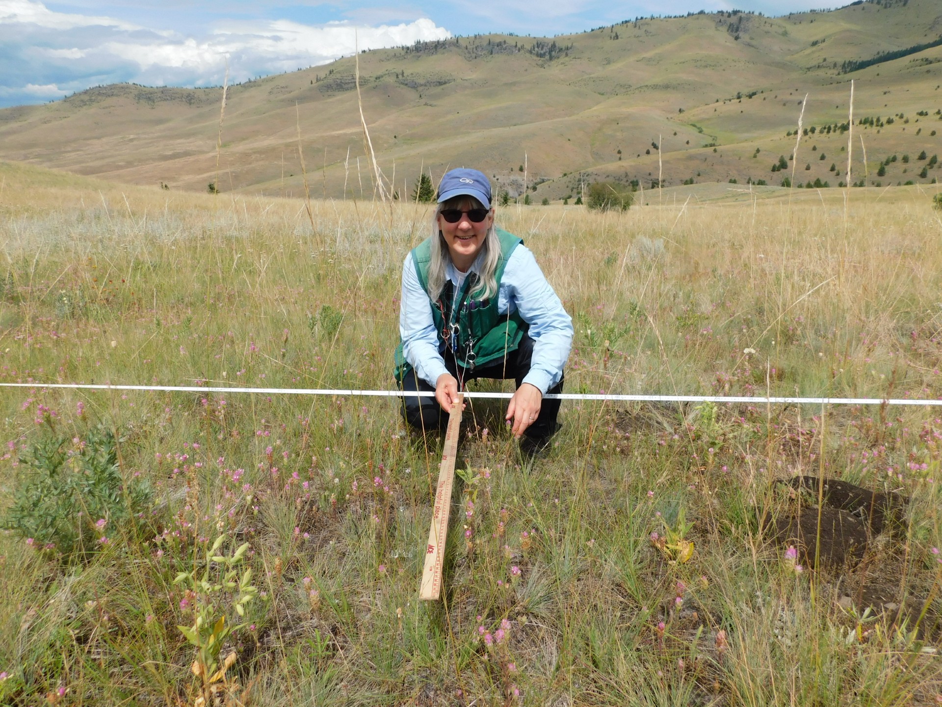 Andrea Pipp in the mountain Prairie holding a yardstick