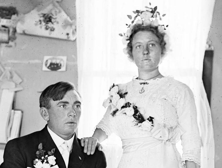 Man sitting in a tux next to woman in a wedding dress