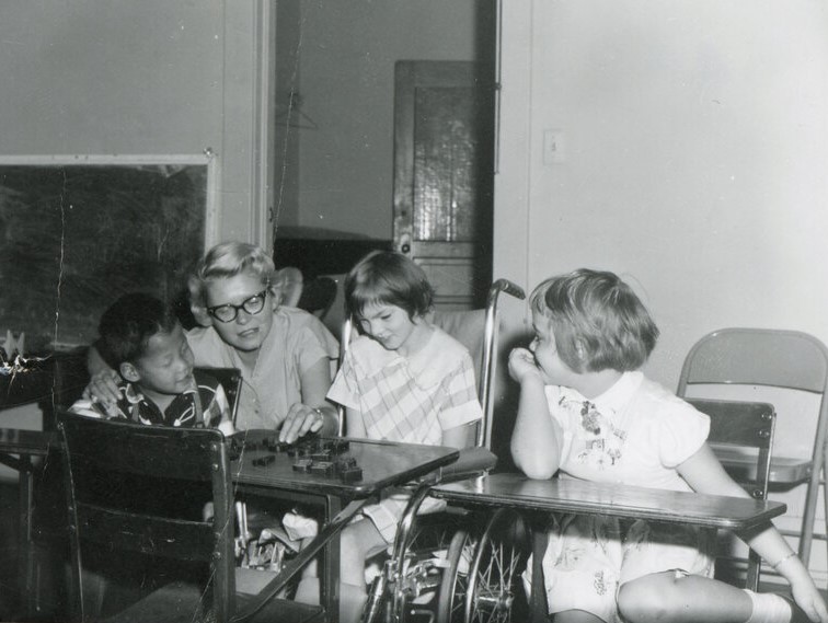 Kids in a classroom with an adult talking to them