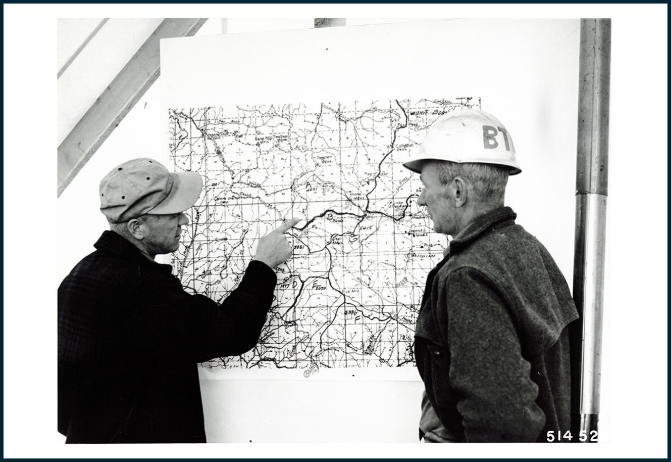 People in hard hats looking at a map on the wall